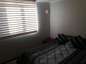 1 dormitorio con 1 cama y ventana con persianas en Bahia horizonte herradura, en Coquimbo