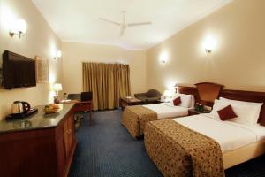 a hotel room with two beds and a television at Hotel Madhuban in Dehradun +24 photos