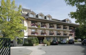 un bâtiment d'hôtel avec des voitures garées dans un parking dans l'établissement Logis Hotel Arc En Ciel, à Thonon-les-Bains