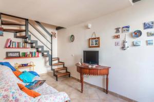 a living room with a couch and a desk with a television at La Casa di Romi in Marina di Ragusa
