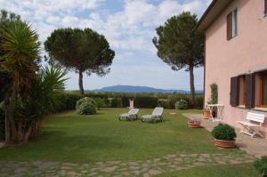 a yard with two chairs and trees and a house at Agriturismo Poggio Campana in San Donato