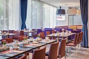 a restaurant with tables and chairs and blue curtains at IntercityHotel Celle in Celle