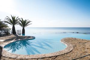 a swimming pool with the ocean in the background at Hotel Costa dei Fiori in Santa Margherita di Pula