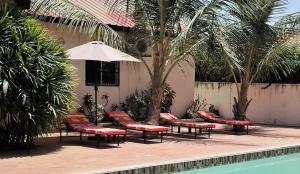 B & B Villa Calliandra في بيجيلو: مجموعة كراسي ومظلة بجانب مسبح
