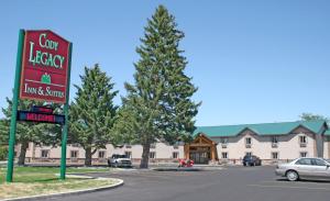 ein Schild vor einem Gasthof und Suiten in der Unterkunft Cody Legacy Inn & Suites in Cody