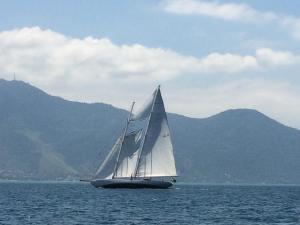 a sail boat in the water with mountains in the background at Conforto e Charme em Ilhabela in Ilhabela