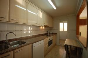 una cocina con armarios blancos y fregadero en Lets Holidays Centric Apartment in Tossa de Mar, en Tossa de Mar