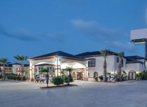 a large building with palm trees in a parking lot at Lone Star Inn - San Benito in San Benito