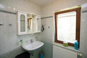 La salle de bains est pourvue d'un lavabo, d'un miroir et d'une fenêtre. dans l'établissement Apartmaji Matej Cvetek, à Bohinj