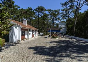 聖佩羅德姆的住宿－Parque De Campismo Orbitur Sao Pedro De Moel，一条鹅卵石街道,旁边是一座树木繁茂的建筑