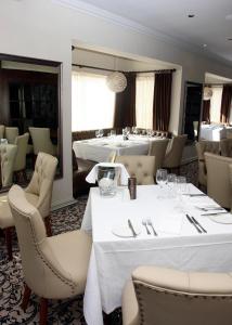 a restaurant with white tables and chairs and a mirror at Trearddur Bay Hotel in Trearddur