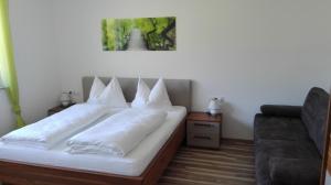 1 dormitorio con cama con almohadas blancas y sofá en Appartement Grießenkareck, en Flachau