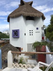 a small white building with a straw roof at Amaranto Bed and Breakfast in Cozumel