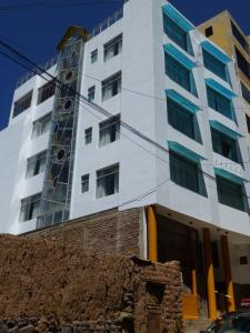 a tall white building with blue windows at Hostal Oscar Inn in Puno