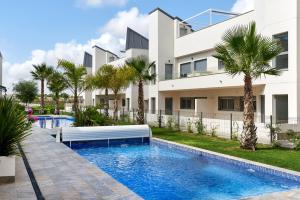 una piscina frente a un edificio con palmeras en Orange Holiday Housing - Villa Amalia 13, en Torrevieja