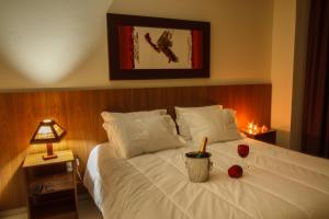 a bedroom with a white bed with a candle on it at Ville de Montagne Hotel in Brumadinho
