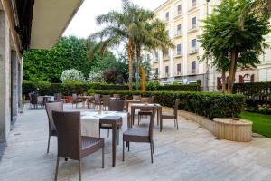 ein Restaurant mit Tischen und Stühlen und ein Gebäude in der Unterkunft Mercure Catania Excelsior in Catania