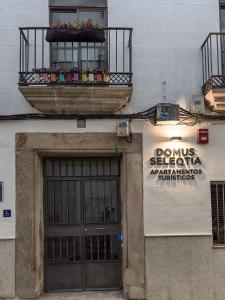 un edificio con una puerta y una señal en él en Apartamentos Turísticos Domus Seleqtia Plaza Mayor en Cáceres