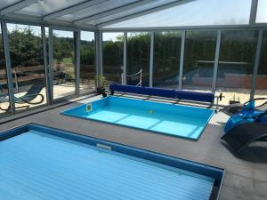 a swimming pool on a patio with a large glass wall at PENZION HNAČOV in Zavlekov
