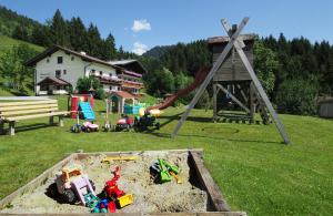 einen Spielbereich mit einem Sandkasten und einem Spielset in der Unterkunft Alpenapartments Unterschlag in Annaberg im Lammertal