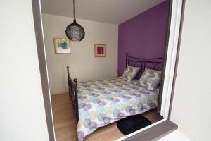 1 dormitorio con 1 cama con pared morada en La Petite Madame, en Moret-sur-Loing
