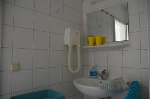 La salle de bains blanche est pourvue d'un lavabo et d'un miroir. dans l'établissement Haus Vineta, à Thiessow