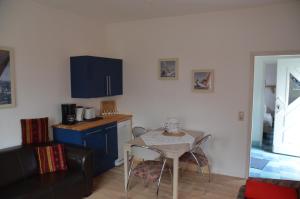 une cuisine avec une table et une petite cuisine avec des placards bleus dans l'établissement Haus Vineta, à Thiessow