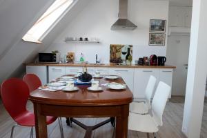 a kitchen with a wooden table and red chairs at Apartament Loft DeLuxe Koszalin in Koszalin