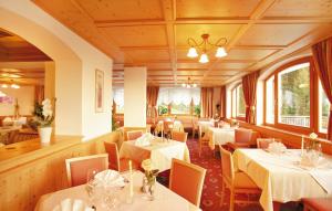 restauracja z białymi stołami, krzesłami i oknami w obiekcie Hotel Plunger w mieście Castelrotto