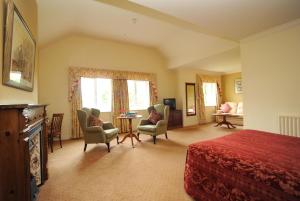 a bedroom with a bed and chairs and a table at Loch Lein Country House in Killarney