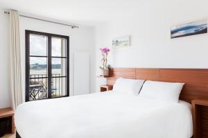 Un dormitorio con una gran cama blanca y una ventana en Hotel du port en Locquirec