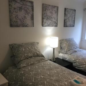 a bedroom with two beds and a lamp and pictures on the wall at West Field Apartment in Glasgow