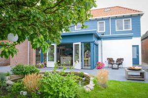 uma casa com uma casa azul e branca em De Moerbei em De Cocksdorp