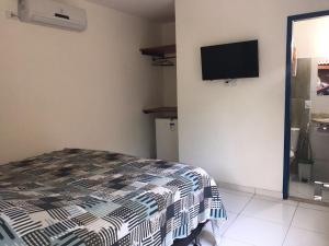 a bedroom with a bed and a flat screen tv on the wall at Recanto das Geraes in Arraial d'Ajuda