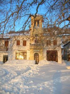 アギオス・ラヴレディオスにあるVillage Houseの雪の中に塔のある大きな石造りの建物