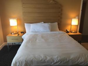 um quarto com uma cama branca e 2 candeeiros em Diamond Head Inn em San Diego