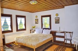 a bedroom with a bed and a desk and windows at Kalinia Guesthouse B&B in Kovachevitsa
