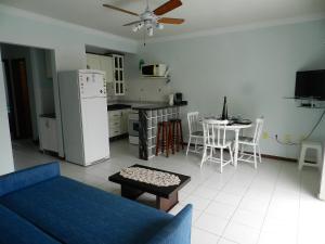 cocina y sala de estar con nevera y mesa. en Residencial Jardim Palmeiras, en Bombinhas