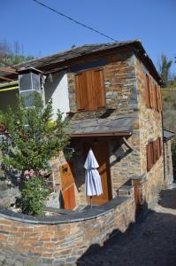 - un bâtiment en pierre avec un parasol devant dans l'établissement Casa da Arvore - Paradinha, à Paradinha