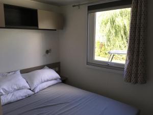 a bedroom with a bed and a window with a table at Fun Family Home - Camping Les Charmettes in Les Mathes