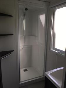a glass shower in a bathroom next to a sink at Fun Family Home - Camping Les Charmettes in Les Mathes