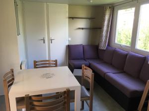 Fun Family Home - Camping Les Charmettes في لو ماثيز: غرفة معيشة مع أريكة أرجوانية وطاولة
