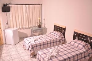 a room with two beds and a table and a television at Hotel Capim Dourado in Palmas