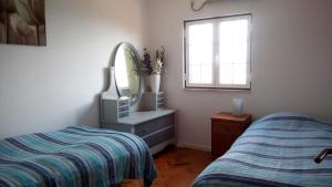 een slaapkamer met een bed, een spiegel en een dressoir bij Logra-Sol in Figueira da Foz