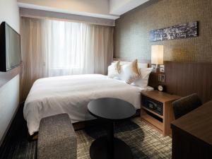 Un pat sau paturi într-o cameră la HOTEL UNIZO Osaka Umeda