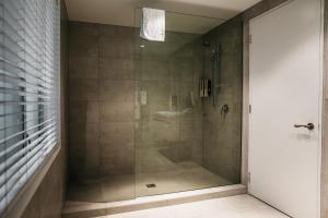 a shower with a glass door in a bathroom at The Grange Motel in Christchurch
