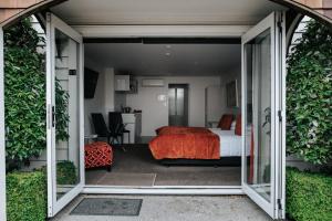 1 dormitorio con 1 cama y puerta corredera de cristal en The Grange Motel en Christchurch