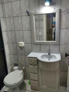 a bathroom with a toilet and a sink and a mirror at Apartamento 3 quartos in Itapema