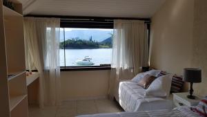 a living room with a window with a boat in the water at Pousada Costa do Sapê in Angra dos Reis +66 photos