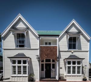 een wit huis met een groen dak bij The Grange B&B in Christchurch